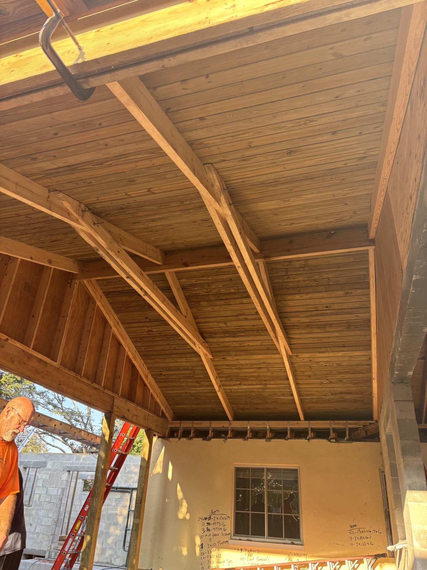 Wooden ceiling construction with sunlight and ladder.